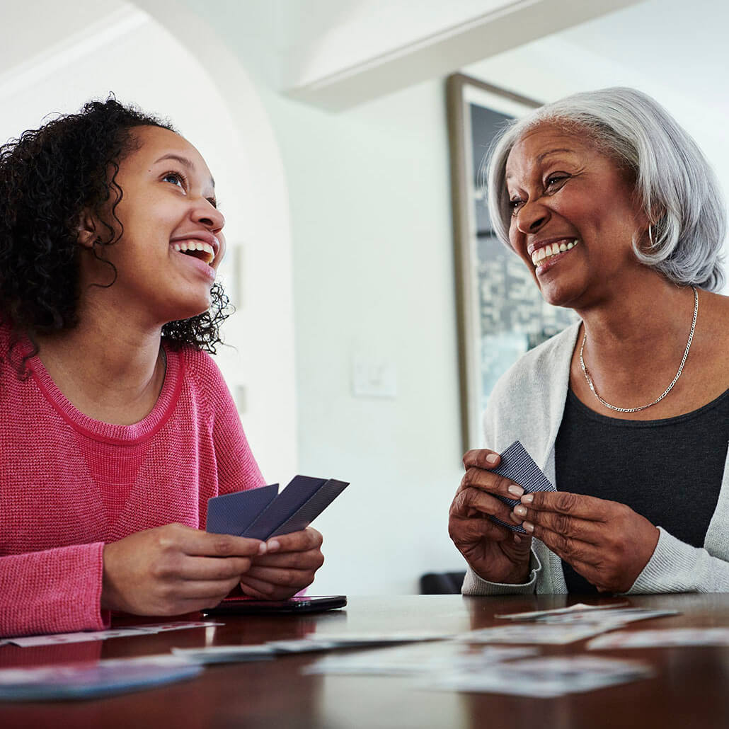 A woman plays a card game with her granddaughter